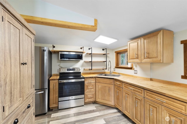 kitchen featuring wood counters, light brown cabinetry, sink, appliances with stainless steel finishes, and light hardwood / wood-style floors