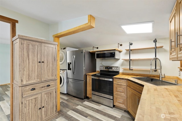 kitchen with stacked washer and clothes dryer, butcher block counters, sink, stainless steel appliances, and light hardwood / wood-style floors