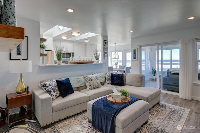 living room featuring a water view, a skylight, and light hardwood / wood-style floors