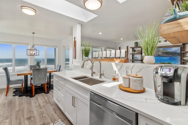 kitchen with pendant lighting, white cabinetry, stainless steel dishwasher, a water view, and light stone countertops