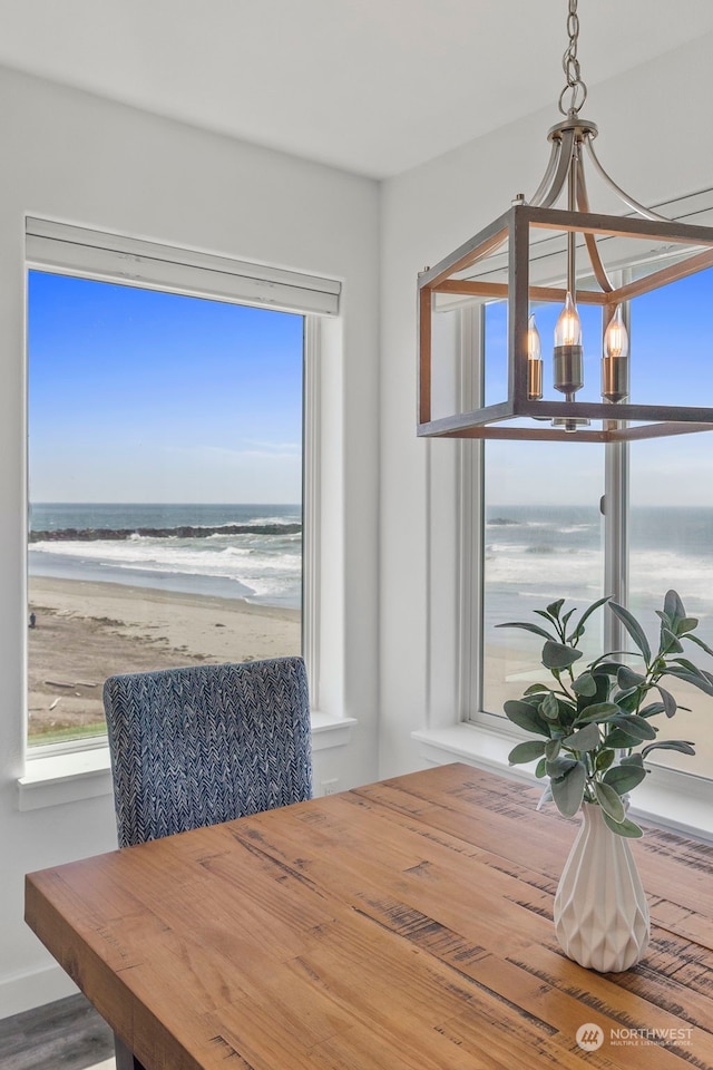 dining room featuring a view of the beach, a wealth of natural light, a chandelier, and a water view