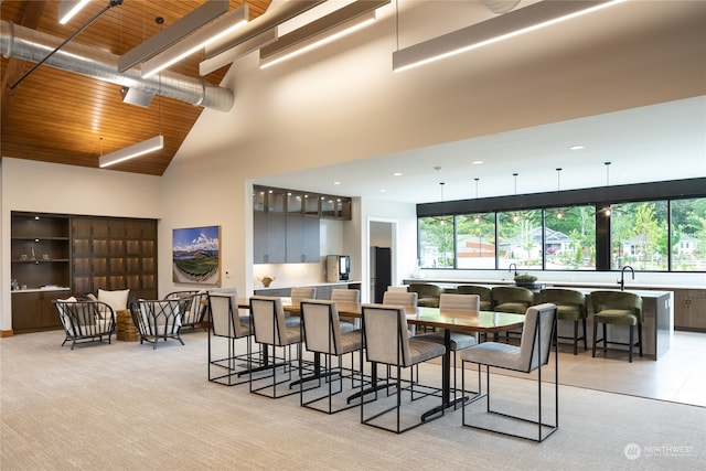 carpeted dining space featuring wood ceiling and a towering ceiling