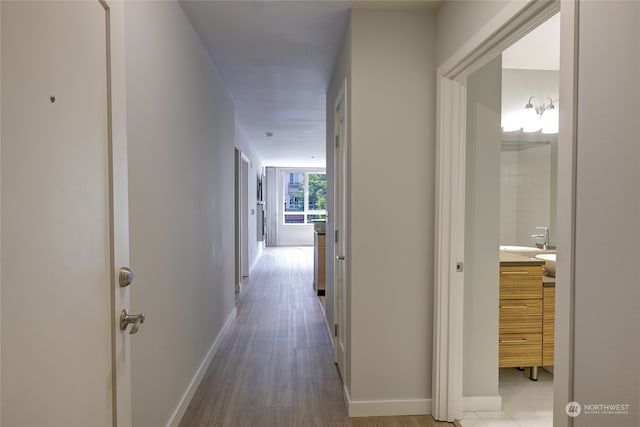 corridor with light hardwood / wood-style floors and sink