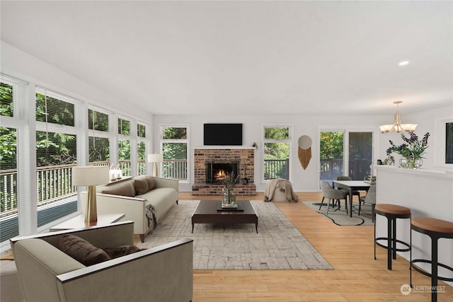 living room featuring a wealth of natural light, a notable chandelier, light hardwood / wood-style floors, and a fireplace