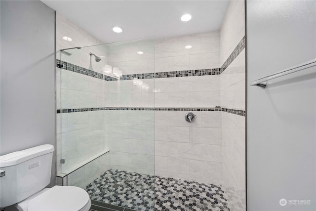 bathroom with tiled shower and toilet