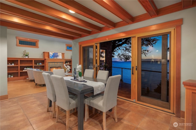 tiled dining space featuring a water view and beamed ceiling