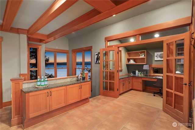 interior space featuring built in desk, a water view, and beamed ceiling