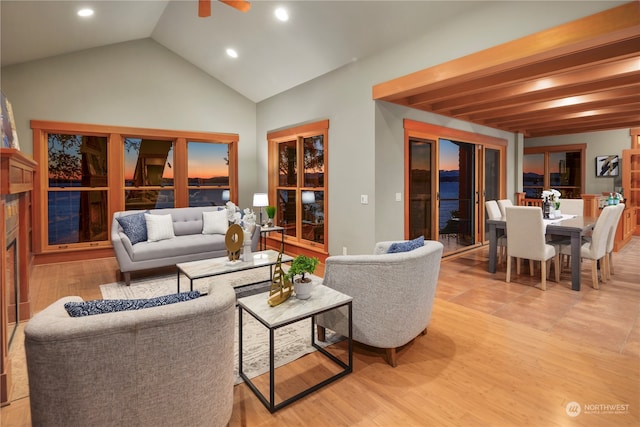 living room featuring vaulted ceiling, light hardwood / wood-style flooring, a fireplace, and ceiling fan