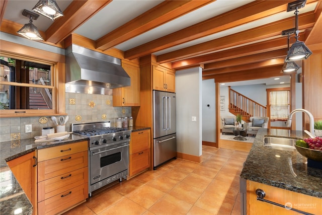 kitchen featuring wall chimney range hood, beamed ceiling, pendant lighting, sink, and premium appliances