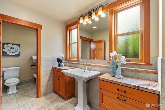 bathroom with toilet, tile walls, and tile patterned flooring