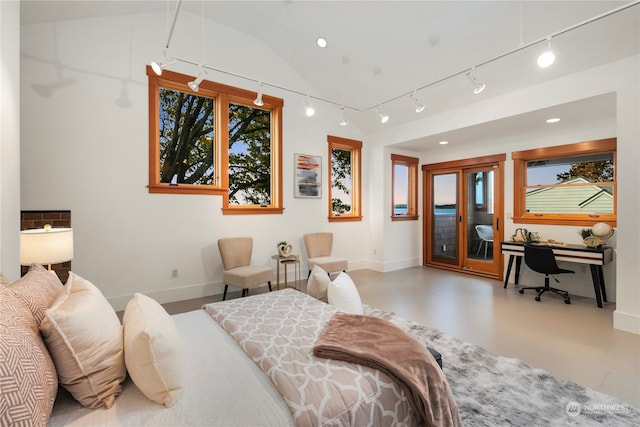 bedroom featuring track lighting, vaulted ceiling, and access to exterior