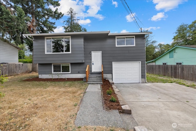 raised ranch featuring a garage and a front lawn