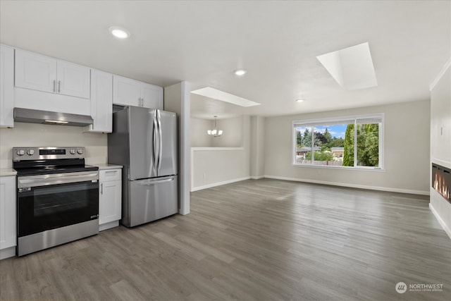 kitchen with a skylight, hardwood / wood-style flooring, and stainless steel appliances