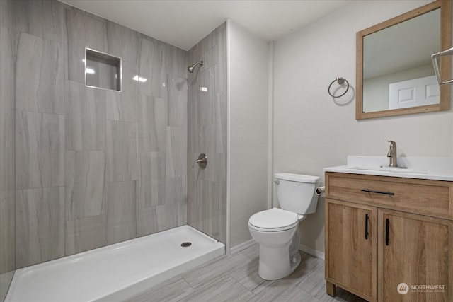 bathroom featuring vanity, toilet, and a tile shower