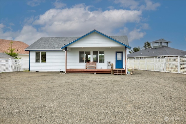 rear view of property featuring a deck, roof with shingles, and a fenced backyard