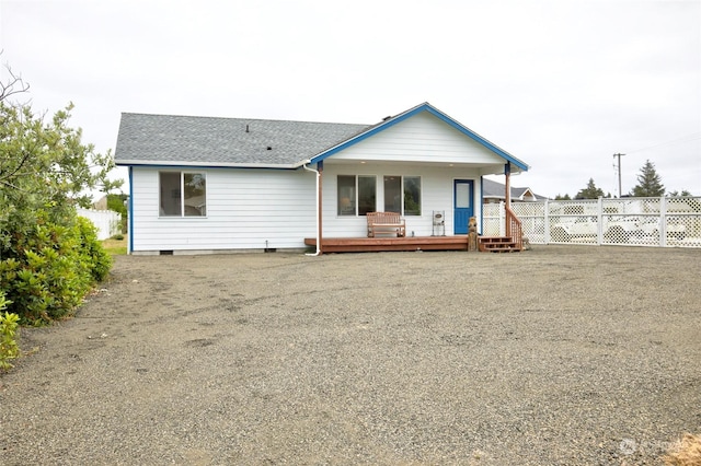 rear view of house with a deck, roof with shingles, and fence