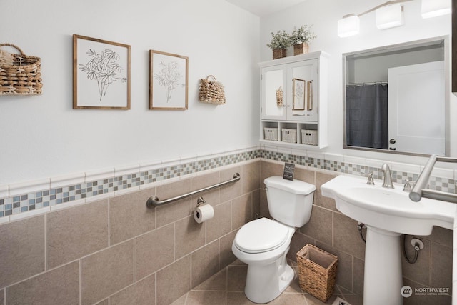 bathroom with toilet and tile walls