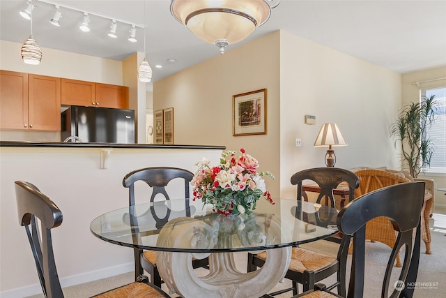 dining space featuring track lighting and light carpet