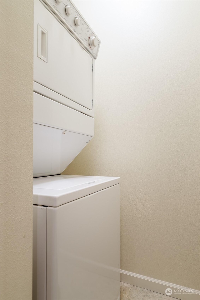 laundry room with light tile patterned flooring and stacked washer and clothes dryer