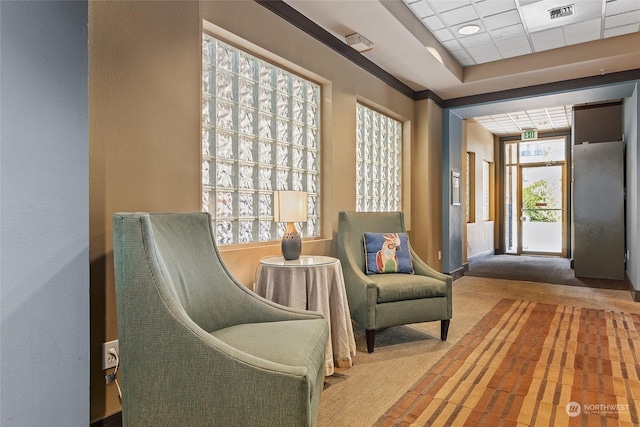 living area featuring a paneled ceiling and carpet