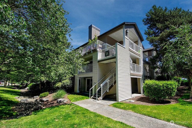 view of side of property featuring a balcony and a lawn