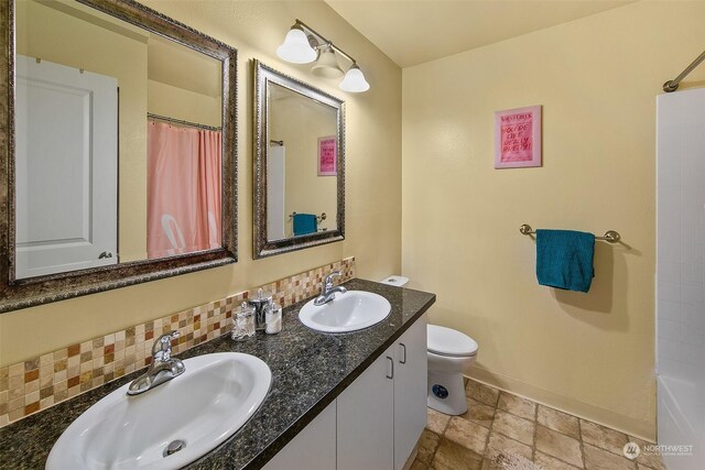 full bathroom with tile patterned flooring, shower / bath combination with curtain, dual bowl vanity, backsplash, and toilet