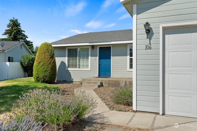 view of front of property with a garage, roof with shingles, and fence