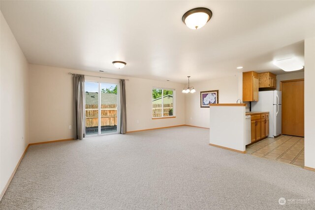 unfurnished living room featuring a chandelier and light colored carpet