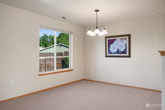 carpeted spare room with a chandelier