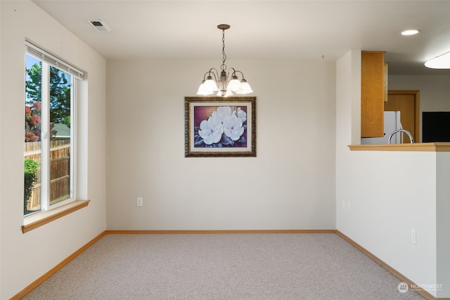 carpeted spare room with a notable chandelier