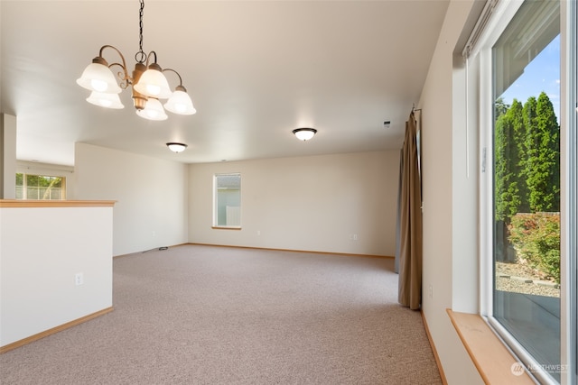 carpeted spare room with a chandelier