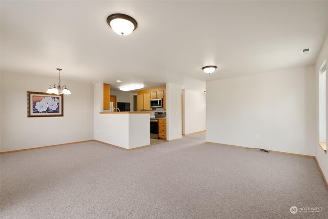 unfurnished living room featuring a notable chandelier and light colored carpet