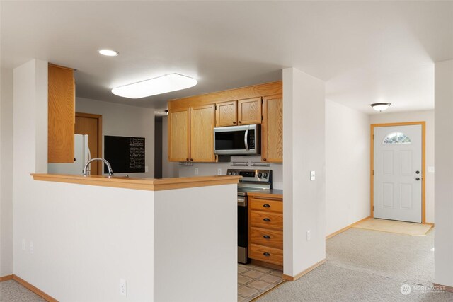 kitchen featuring light colored carpet, appliances with stainless steel finishes, sink, and kitchen peninsula