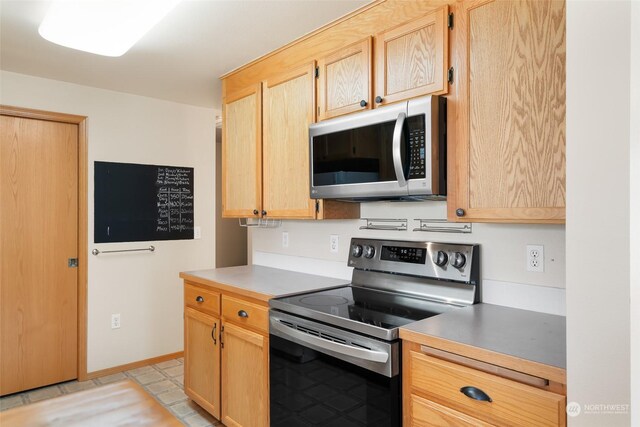 kitchen with light tile patterned flooring, light brown cabinets, and appliances with stainless steel finishes