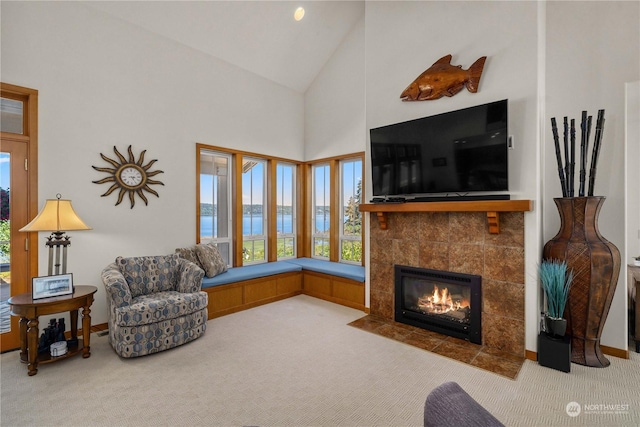 carpeted living room with high vaulted ceiling and a tile fireplace