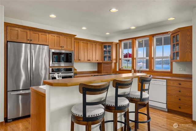 kitchen featuring a kitchen bar, light hardwood / wood-style floors, and appliances with stainless steel finishes