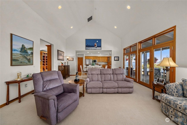 carpeted living room featuring high vaulted ceiling and french doors