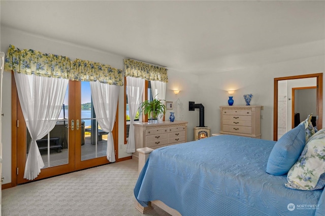 bedroom with french doors, a water view, a wood stove, light colored carpet, and access to exterior