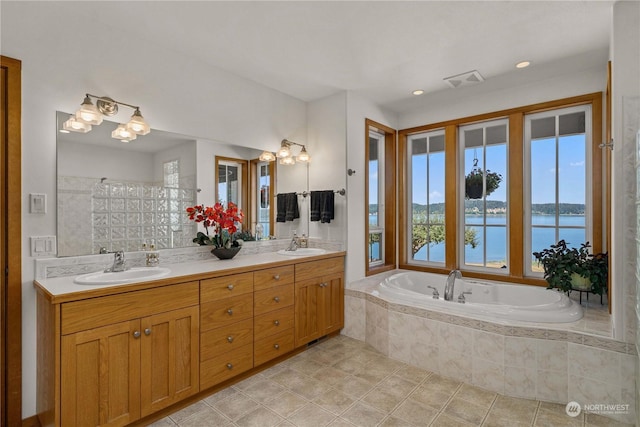 bathroom with a water view, vanity, tiled bath, and tile patterned flooring