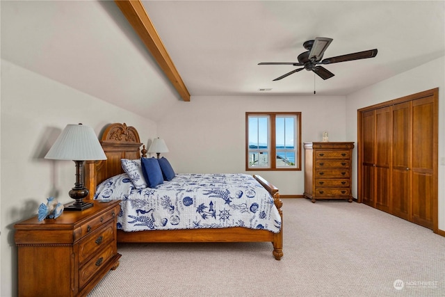 carpeted bedroom featuring ceiling fan, lofted ceiling with beams, and a closet