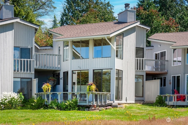 rear view of house featuring a lawn and a balcony