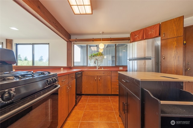 kitchen with black appliances, sink, light tile patterned floors, and decorative light fixtures