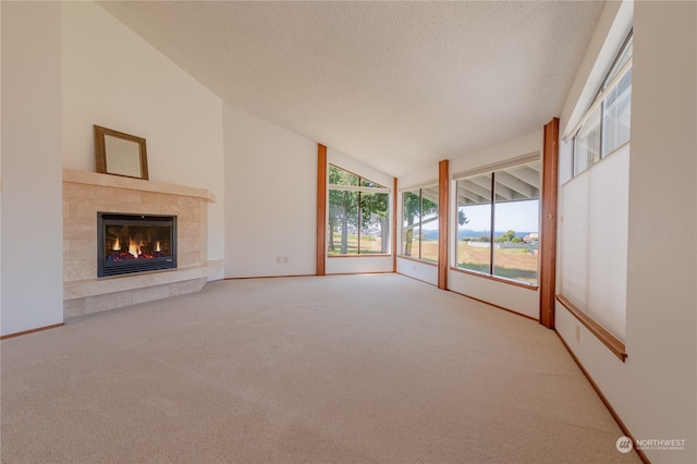 unfurnished living room featuring a textured ceiling, carpet flooring, high vaulted ceiling, and a tile fireplace