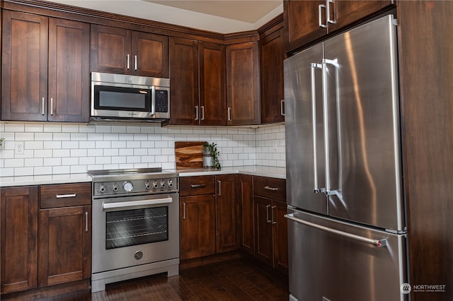 kitchen with premium appliances, dark hardwood / wood-style flooring, backsplash, and dark brown cabinetry