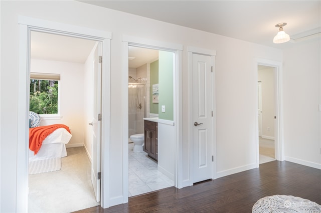 bedroom with ensuite bath and hardwood / wood-style floors