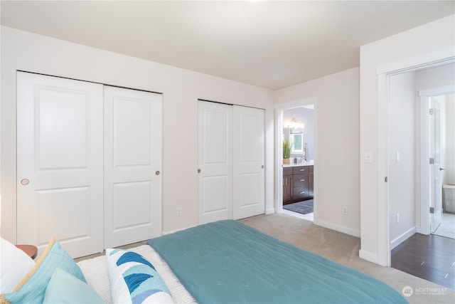 carpeted bedroom with two closets and connected bathroom