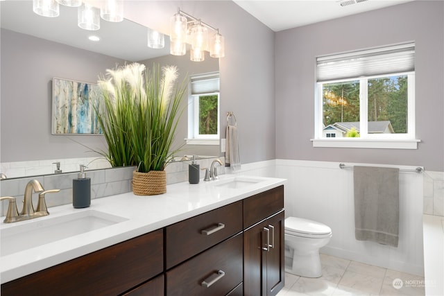 bathroom featuring tile patterned floors, toilet, and dual bowl vanity