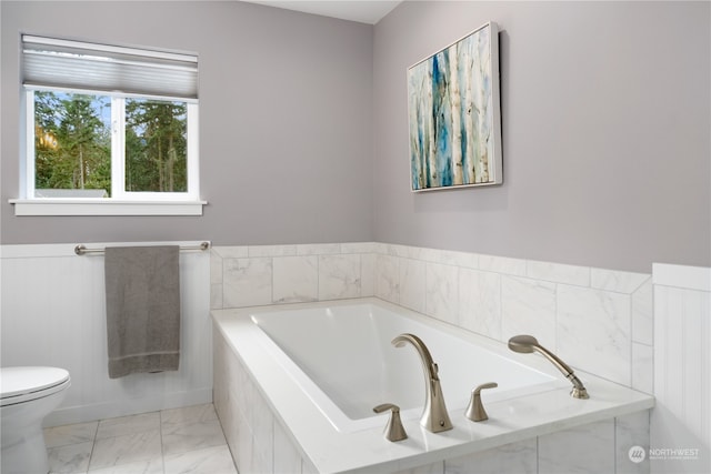 bathroom featuring toilet, tile patterned floors, and a relaxing tiled tub