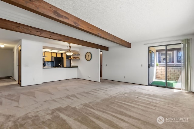 unfurnished living room with sink, beamed ceiling, carpet, and a textured ceiling