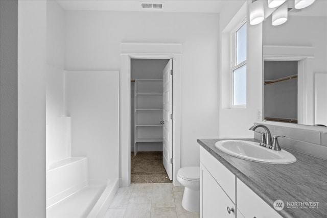 bathroom featuring walk in shower, vanity, and toilet